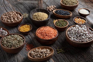 Vegan protein source.Various assortment of legumes, lentils, chickpea and beans assortment in different bowls on wooden table. Top view.