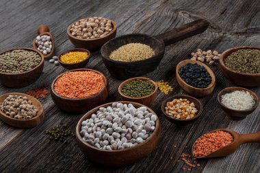 Vegan protein source.Various assortment of legumes, lentils, chickpea and beans assortment in different bowls on wooden table. Top view.