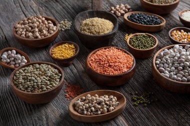 Vegan protein source.Various assortment of legumes, lentils, chickpea and beans assortment in different bowls on wooden table. Top view.