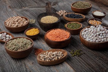 Vegan protein source.Various assortment of legumes, lentils, chickpea and beans assortment in different bowls on wooden table. Top view.