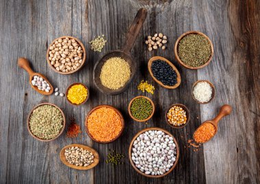 Vegan protein source.Various assortment of legumes, lentils, chickpea and beans assortment in different bowls on wooden table. Top view.