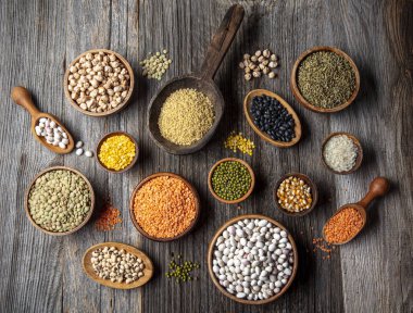 Vegan protein source.Various assortment of legumes, lentils, chickpea and beans assortment in different bowls on wooden table. Top view.