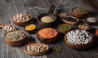 Vegan protein source.Various assortment of legumes, lentils, chickpea and beans assortment in different bowls on wooden table. Top view.