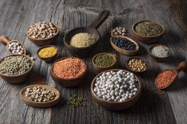 Vegan protein source.Various assortment of legumes, lentils, chickpea and beans assortment in different bowls on wooden table. Top view.