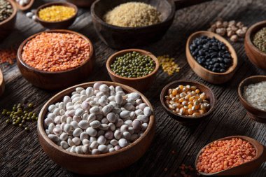 Vegan protein source.Various assortment of legumes, lentils, chickpea and beans assortment in different bowls on wooden table. Top view.