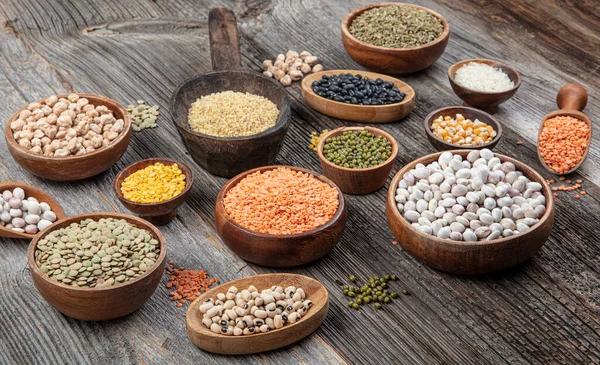 Vegan protein source.Various assortment of legumes, lentils, chickpea and beans assortment in different bowls on wooden table. Top view.