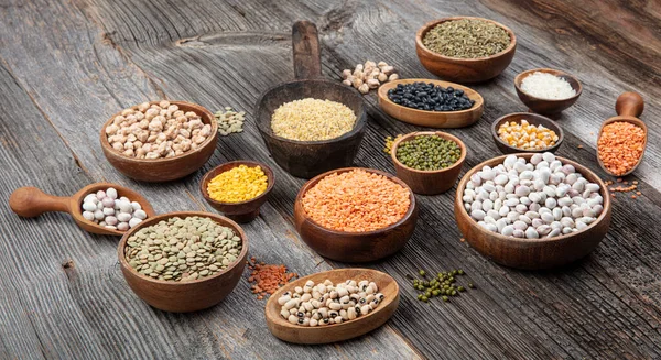 Vegan protein source.Various assortment of legumes, lentils, chickpea and beans assortment in different bowls on wooden table. Top view.
