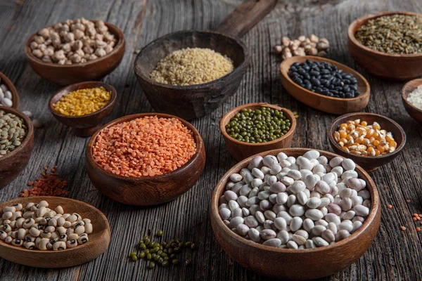 Vegan protein source.Various assortment of legumes, lentils, chickpea and beans assortment in different bowls on wooden table. Top view.