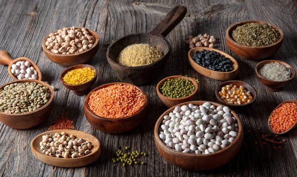 Vegan protein source.Various assortment of legumes, lentils, chickpea and beans assortment in different bowls on wooden table. Top view.