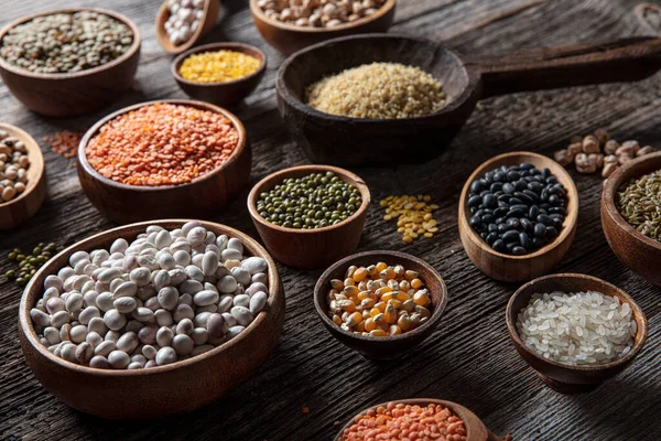 Vegan protein source.Various assortment of legumes, lentils, chickpea and beans assortment in different bowls on wooden table. Top view.