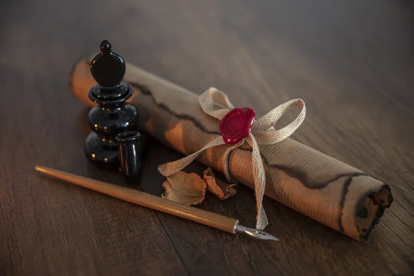 Photograph of a fountain pen with an old inkwell and several differently shaped nibs on papyrus with examples of calligraphy.