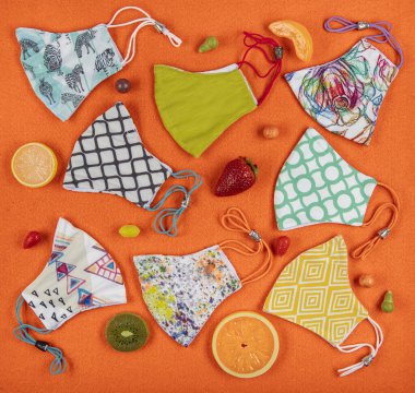 Pamuk kumaştan yapılmış el yapımı çiçek desenli kumaş maske. Turuncu arka planda renkli meyve çeşitleri olan sevimli maskeler. Sağlıklı yaşam tarzı kavramı.