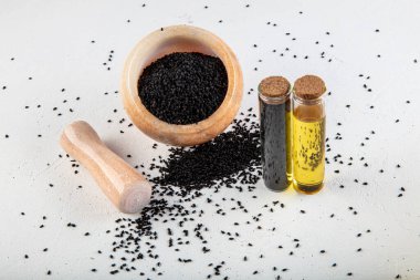 Kasede siyah kimyon tohumları ve cam şişede gerekli yağ. Beyaz arkaplanda Nigella sativa izole. 