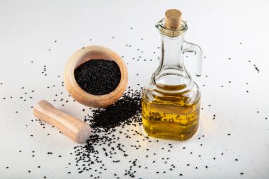 Kasede siyah kimyon tohumları ve cam şişede gerekli yağ. Beyaz arkaplanda Nigella sativa izole. 