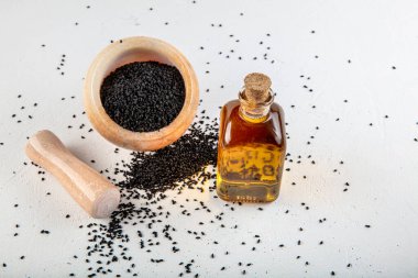 Kasede siyah kimyon tohumları ve cam şişede gerekli yağ. Beyaz arkaplanda Nigella sativa izole. 