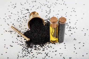 Kasede siyah kimyon tohumları ve cam şişede gerekli yağ. Beyaz arkaplanda Nigella sativa izole. 