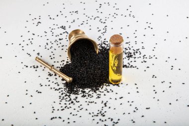 Kasede siyah kimyon tohumları ve cam şişede gerekli yağ. Beyaz arkaplanda Nigella sativa izole. 
