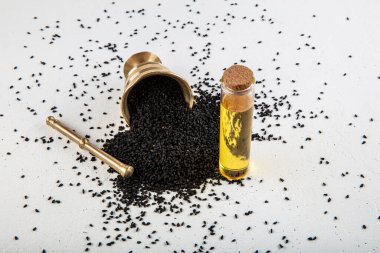 Kasede siyah kimyon tohumları ve cam şişede gerekli yağ. Beyaz arkaplanda Nigella sativa izole. 