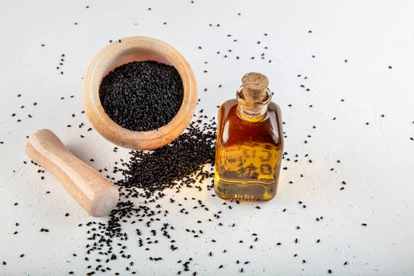 Kasede siyah kimyon tohumları ve cam şişede gerekli yağ. Beyaz arkaplanda Nigella sativa izole. 