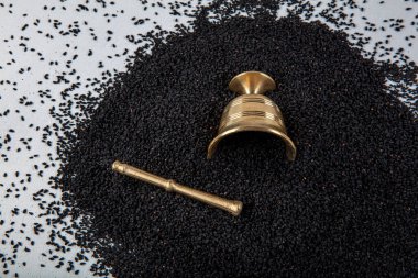 Nigella sativa tohumları ayrıca siyah kimyon, kalo jeera, kalonji ve siyah karanfil olarak da bilinir demir kepçesinde ve beyaz ahşap zemin üzerinde havan ve kopyalama alanı ile birlikte.