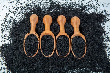 Siyah kimyon tohumları, doğal antioksidan. Kara kimyon tohumları ahşap kaşıkla ya da tahta arka planda kürekle gerekli yağ. Birçok hastalık için organik bitkisel ilaç.