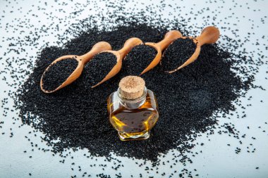 Siyah kimyon tohumları, doğal antioksidan. Kara kimyon tohumları ahşap kaşıkla ya da tahta arka planda kürekle gerekli yağ. Birçok hastalık için organik bitkisel ilaç.