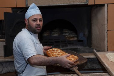 Geleneksel yöntemle ahşap fırınla pişirilmiş günlük ekmek üretimi. Fırıncı Türk pide ekmeği yapıyor. Fırından taze Türk pide ekmeği alıyor. Türk Ramazan Pita üretim süreci.