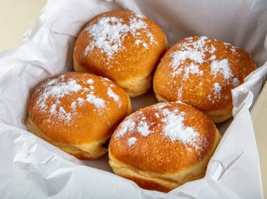 Taze pişmiş ve pudra şekerli Alman çörekleriyle süslenmiş - Berliner ya da Krapfen - beyaz masada..