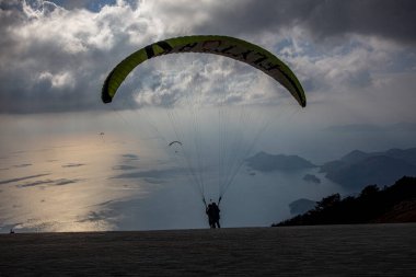 FethiyeOludeniz Babada dünyanın en önemli yamaç paraşütü bölgelerinden biri olarak kabul edilir. Mula, Türkiye. Cesur paraşütçüler Oludeniz tatil köyü yakınlarındaki Babadag dağından havalandılar.. 