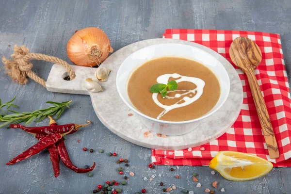 French Onion Soup in a ceramic bowl with ingredients in the background. Onion soup with croutones and creamed cheese.