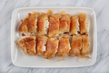 Türk usulü doldurulmuş filo hamuru borek Kol Boregi servis ediyordu. Peynir ve kıymalı turta mermer arka planda dilimlenir. Türkçe adı: Kol Boregi.