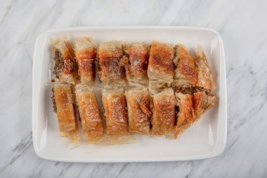 Türk usulü doldurulmuş filo hamuru borek Kol Boregi servis ediyordu. Peynir ve kıymalı turta mermer arka planda dilimlenir. Türkçe adı: Kol Boregi.