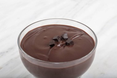 Şam fıstıklı profiteroller cam kasede / pakette. Erimiş siyah çikolatayla profiterol kulesinin tepesinde.