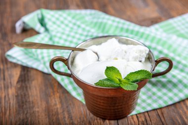 Bakır kasede mayalanmış bufalo yoğurdu. Ev yapımı yoğurt, ahşap masada, üst manzara, kopyalama alanı. Sağlıklı kahvaltı tarifleri için organik sade Yunan yoğurdu.
