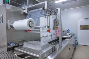 Yiyecek endüstrisi fabrikasındaki gıda vakum ambalaj makinesinde tereyağı ve peynir ambalajının işlenmesi. Yemek tereyağı ve peynir paketliyorum. Elektrik süpürgesi..
