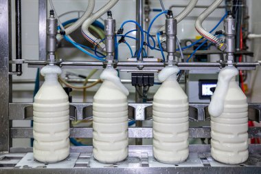 Fabrikada sütü plastik şişelere dolduruyorum. Mandıra fabrikasındaki ekipman. Süt şişeleme makinesi.