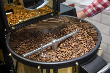 Kahve kızartma makinesi. Kavrulmuş kahve çekirdeği eli. Kapatın.