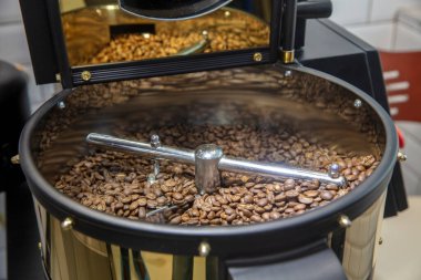 Kahve kızartma makinesi. Kavrulmuş kahve çekirdeği eli. Kapatın.