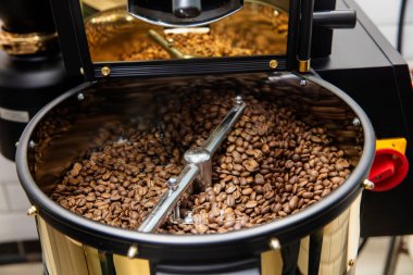 Kahve kızartma makinesi. Kavrulmuş kahve çekirdeği eli. Kapatın.