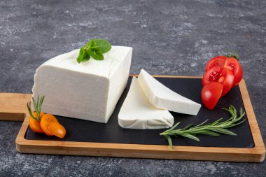 Dilimlenmiş Feta peyniri. Tahtada domatesli taze peynir..