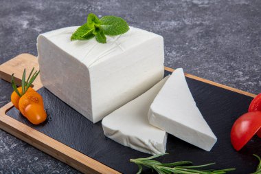 Dilimlenmiş Feta peyniri. Tahtada domatesli taze peynir..