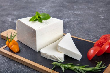 Dilimlenmiş Feta peyniri. Tahtada domatesli taze peynir..