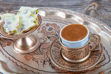 Ahşap arka planda eski model fincana Türk kahvesi dökmek. Türk kahvesi bakır Türkler ve tahıllar ahşap yüzeye saçıldı.