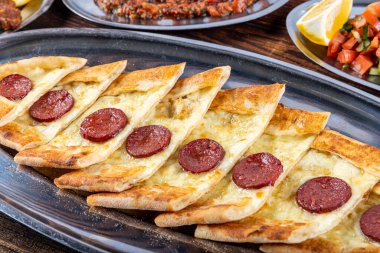 Pide, Türk teknesi sosisli (sucuk) ve baharatlı ve otlu düz ekmek şeklinde. Biberli ve peynirli Türk pide tabağı. Türkçe adı: Sucuklu pide.