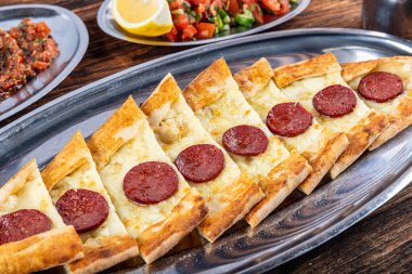 Pide, Türk teknesi sosisli (sucuk) ve baharatlı ve otlu düz ekmek şeklinde. Biberli ve peynirli Türk pide tabağı. Türkçe adı: Sucuklu pide.