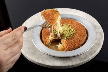 Türk tatlısı, kunafa, kaday fıstığı tozu ve peynirli, sıcak, çok tatlı. Siyah zemin üzerine geleneksel Türk tatlısı.