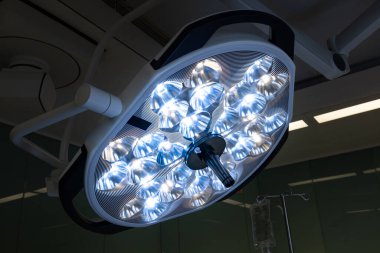 Steril bir ameliyathaneyi aydınlatan, tıbbi prosedürler ve ameliyatlar için parlak, odaklı aydınlatma sağlayan ameliyat ışıkları..