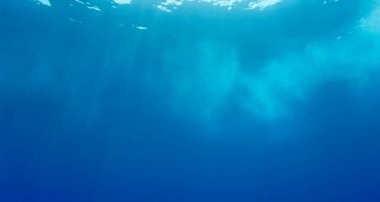 Mavi okyanusun yüzeyinden gelen güneş ışınlarının sualtı fotoğrafı. Soyut arkaplanlar.