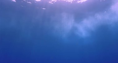 Mavi okyanusun yüzeyinden gelen güneş ışınlarının sualtı fotoğrafı. Soyut arkaplanlar.