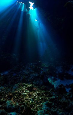 Işık katedralleri. Mağaradaki sihirli güneş ışınlarının sanatsal sualtı fotoğrafı. Tüplü dalış sanatı.